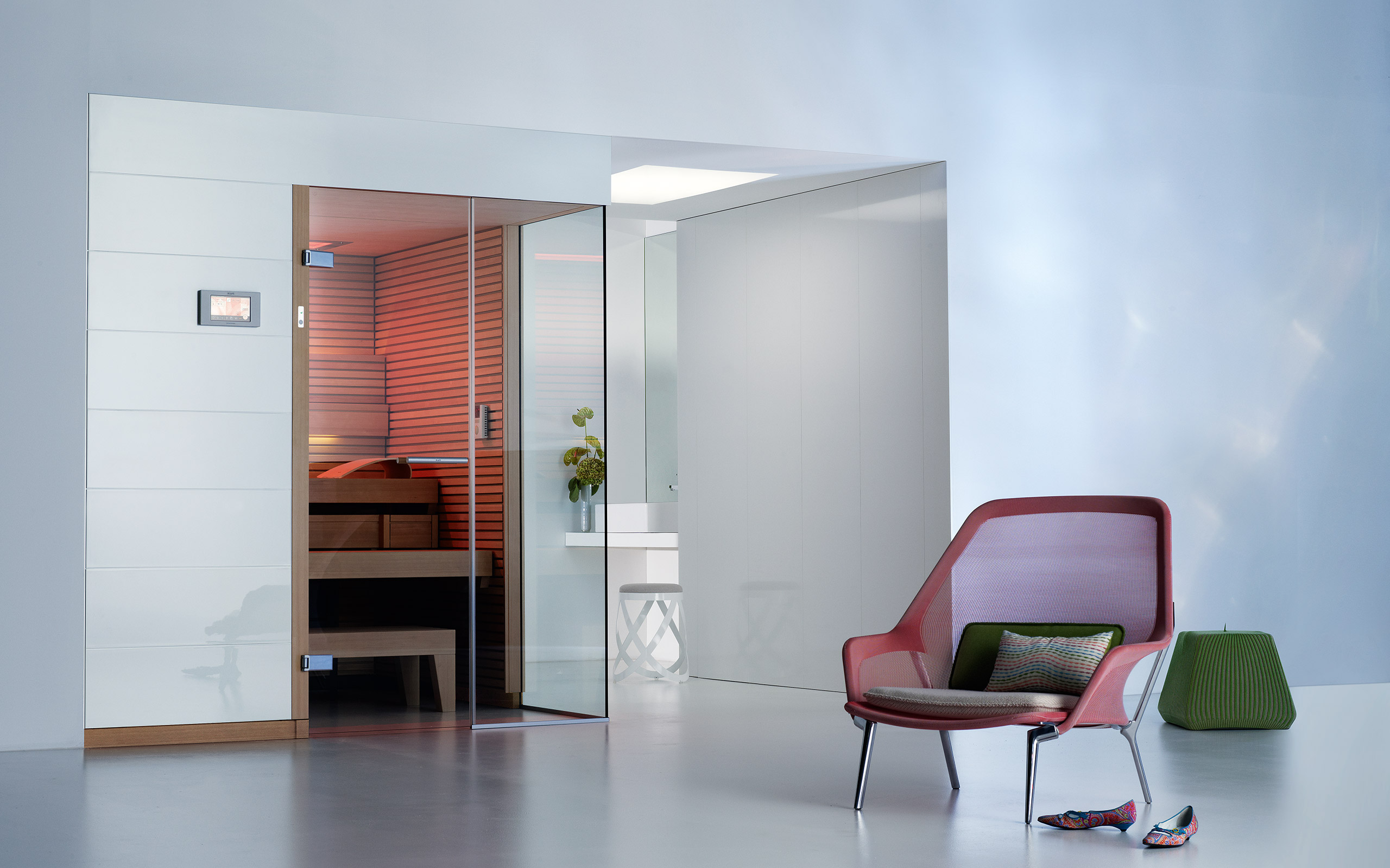 Preprosta finska savna čistega izgleda. Belo pročelje in eleganca. Svetel bel prostor z elementi rdeče in zelene barve.